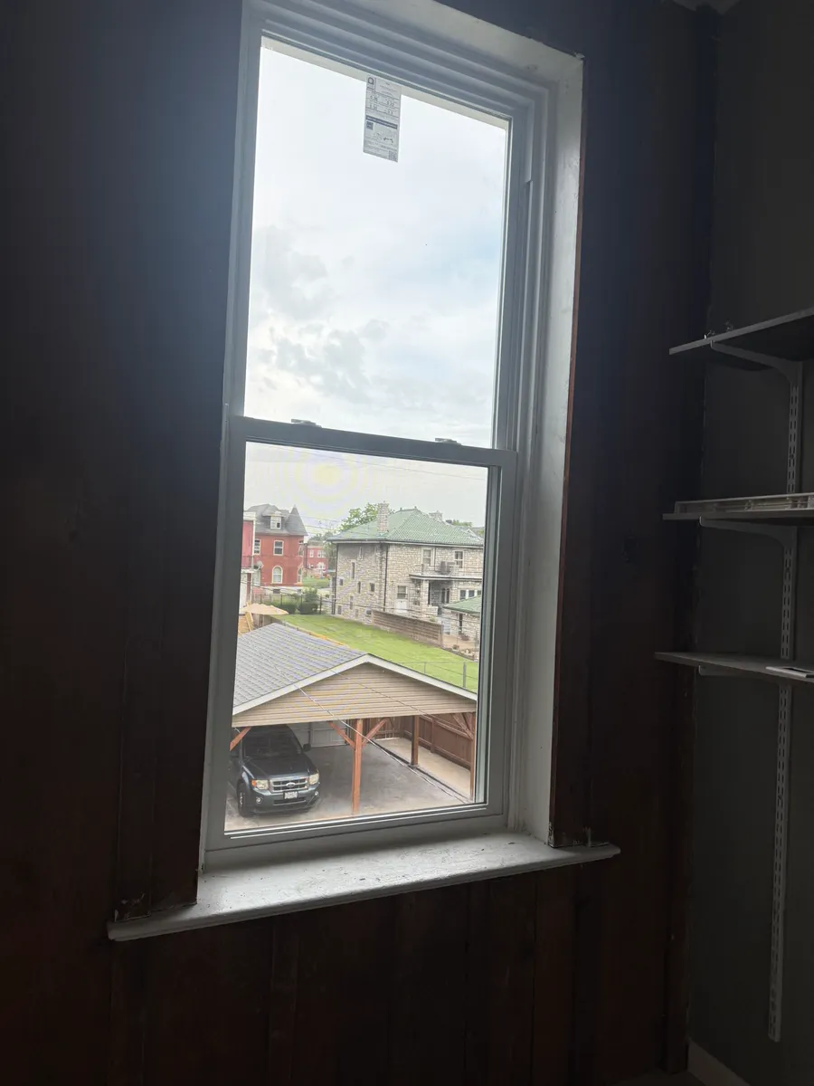New white double-hung replacement window with a clean sill, photographed from inside the same style of opening after installation