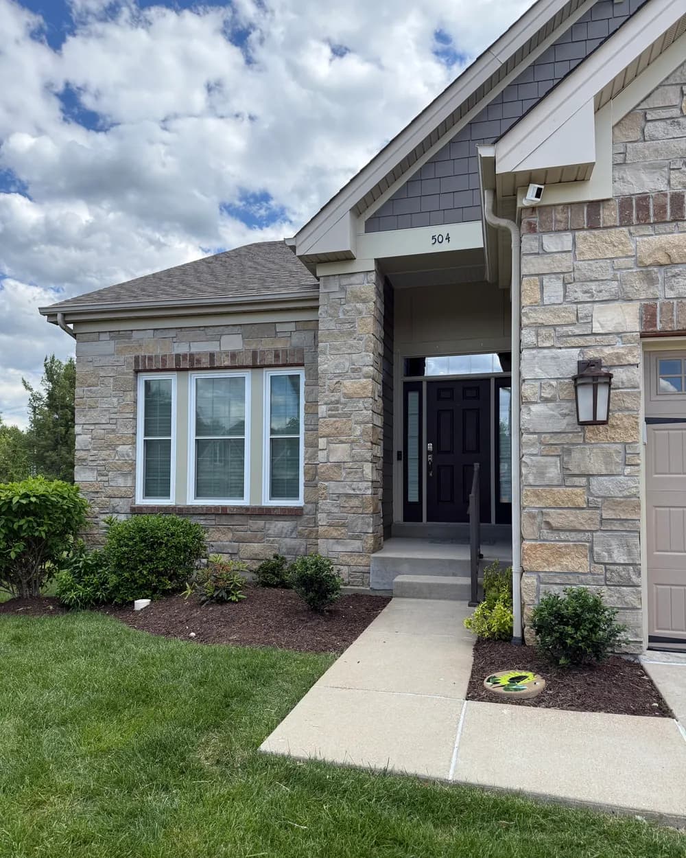 Finished stone home entry with a new dark entry door and new white windows