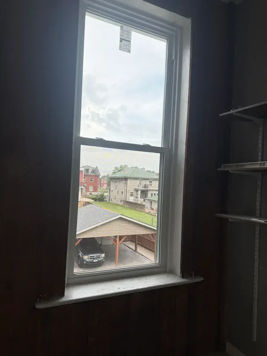 New white double-hung replacement window with a clean sill, photographed from inside the same style of opening after installation
